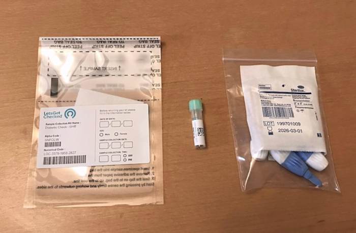 The LetsGetChecked Diabetes test sample collection bag, vial and lancets on a wooden table.